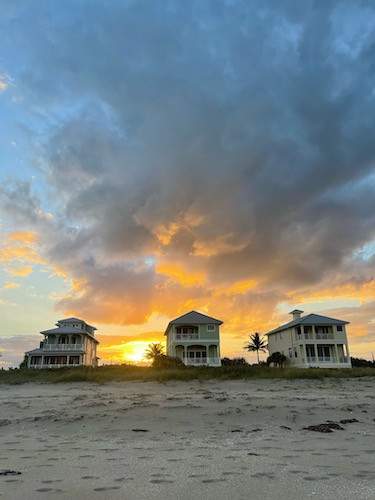 Beach view of houses with beautiful sunset behind them